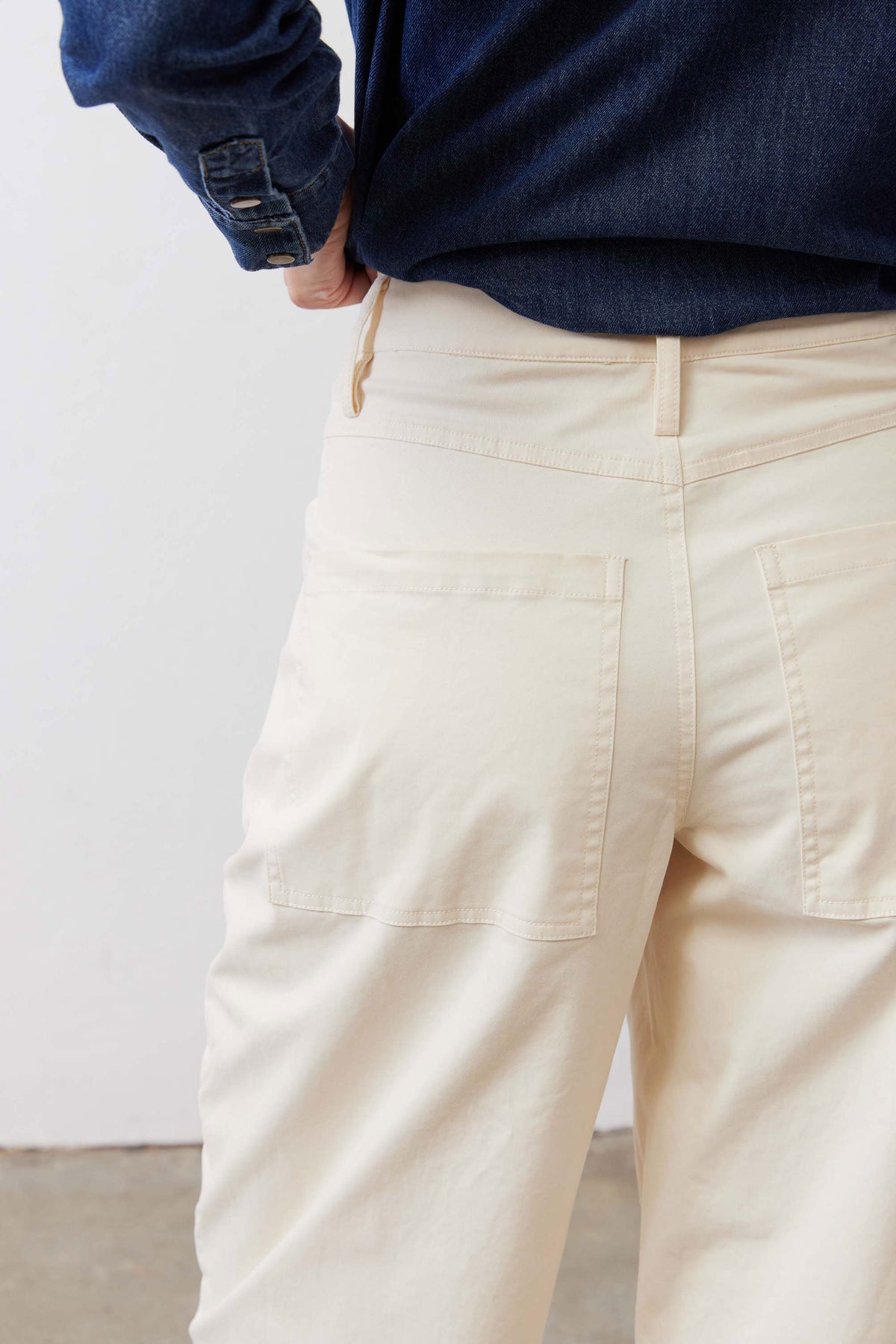 Ecru twill pants detail: patch-style back pocket and front seam lines