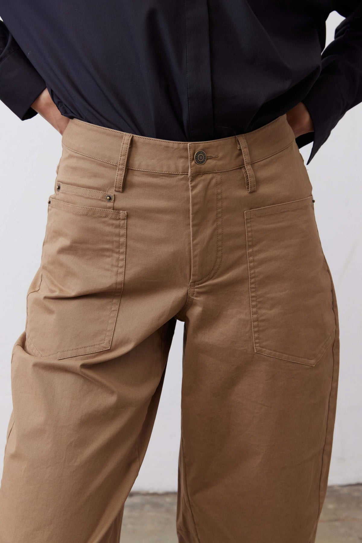 Tan twill pants close-up of cargo pocket, visible stitching, and buttoned waistband