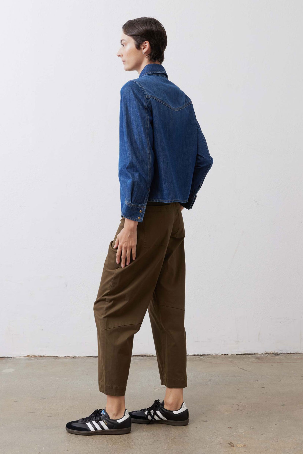 Olive slouchy twill pants from side view with belt loops and cuffed hem.