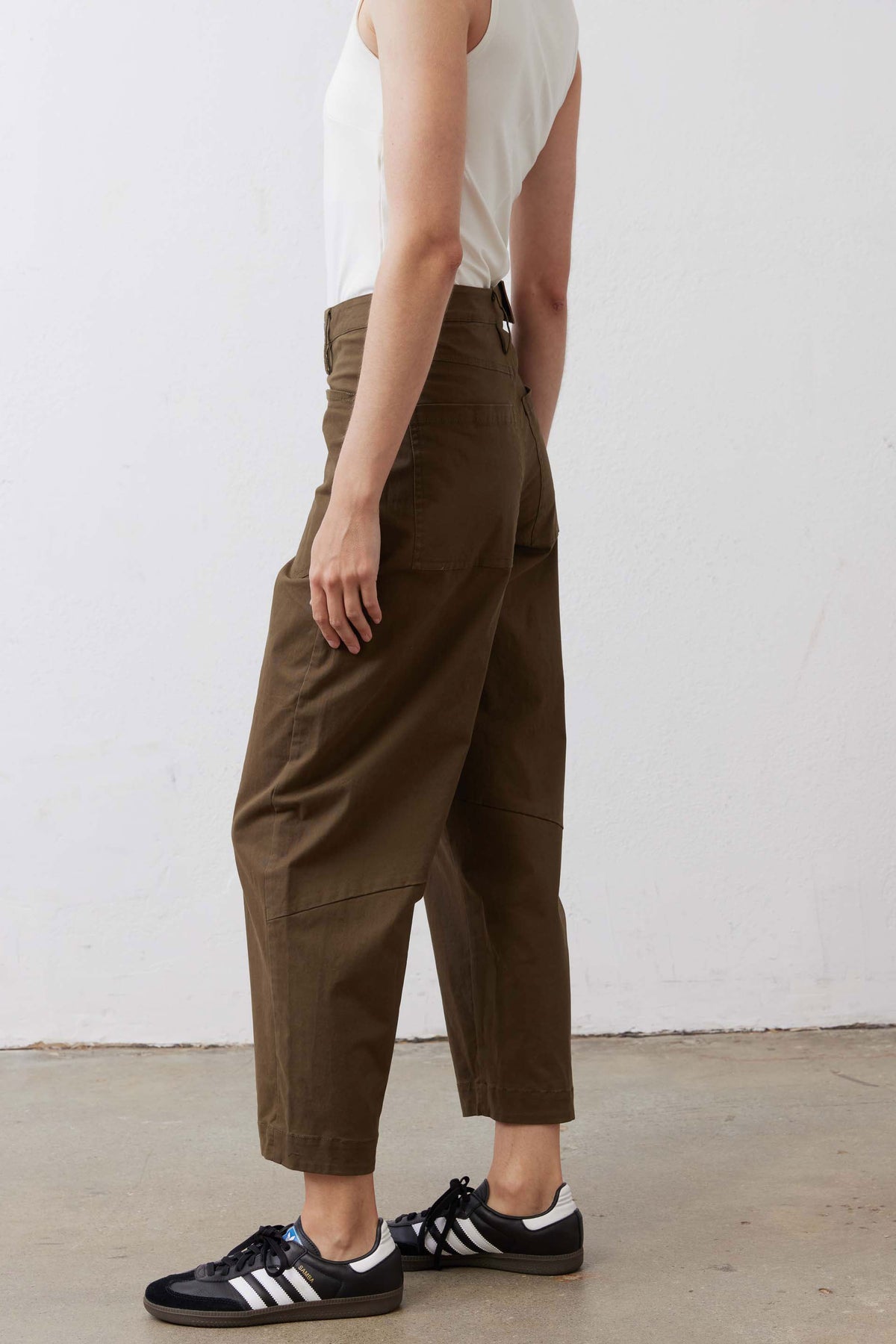 Olive slouchy twill pants side profile with front pockets and cuffed ankle hem.