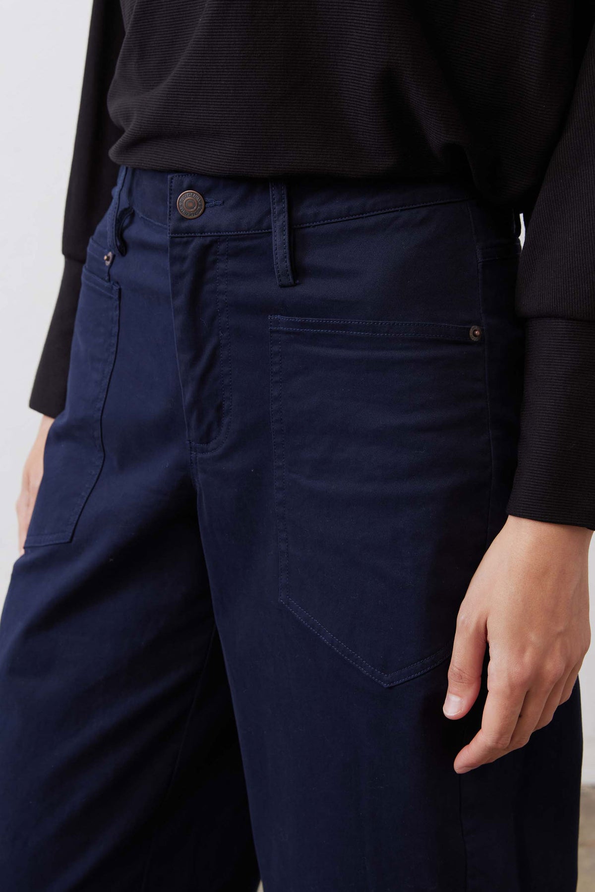 Washed navy twill pants close-up with button waist and front patch pocket detail