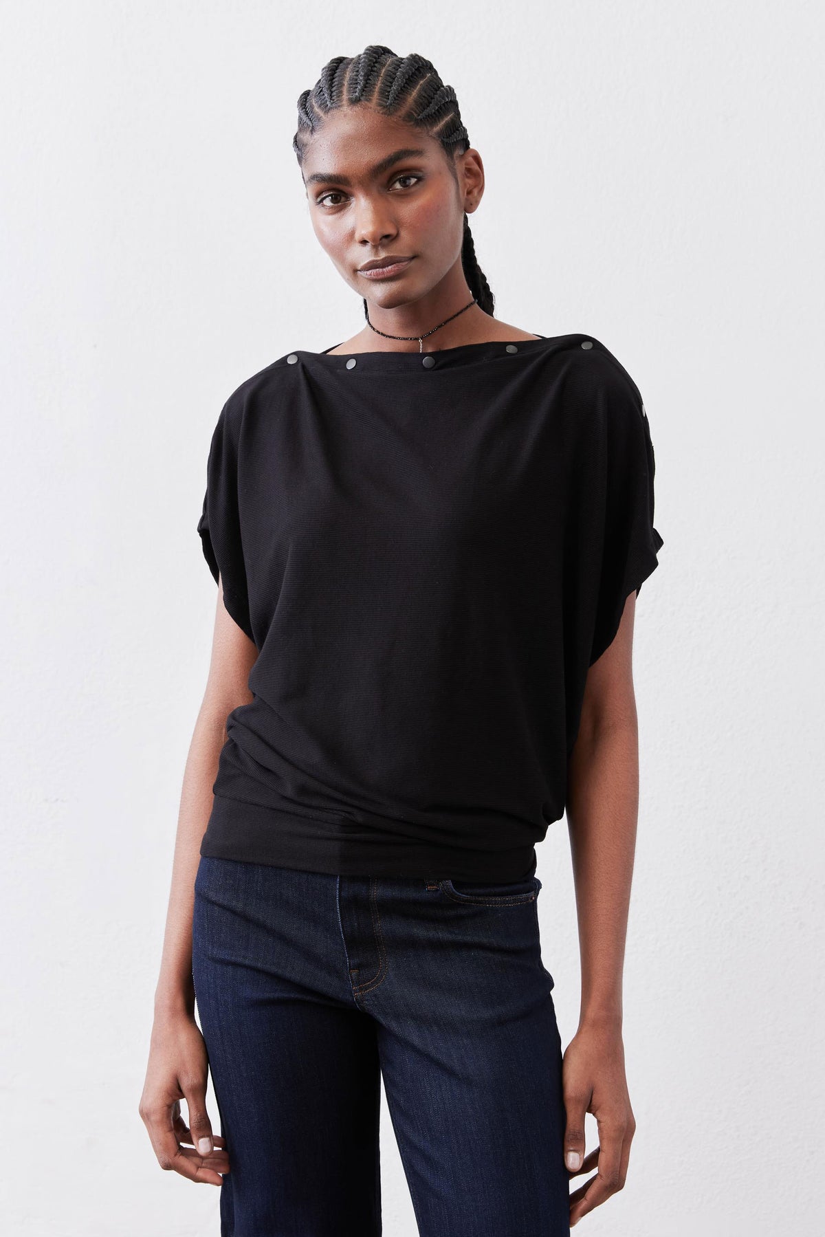 Black short-sleeve top with crew neck and snap-button shoulder details