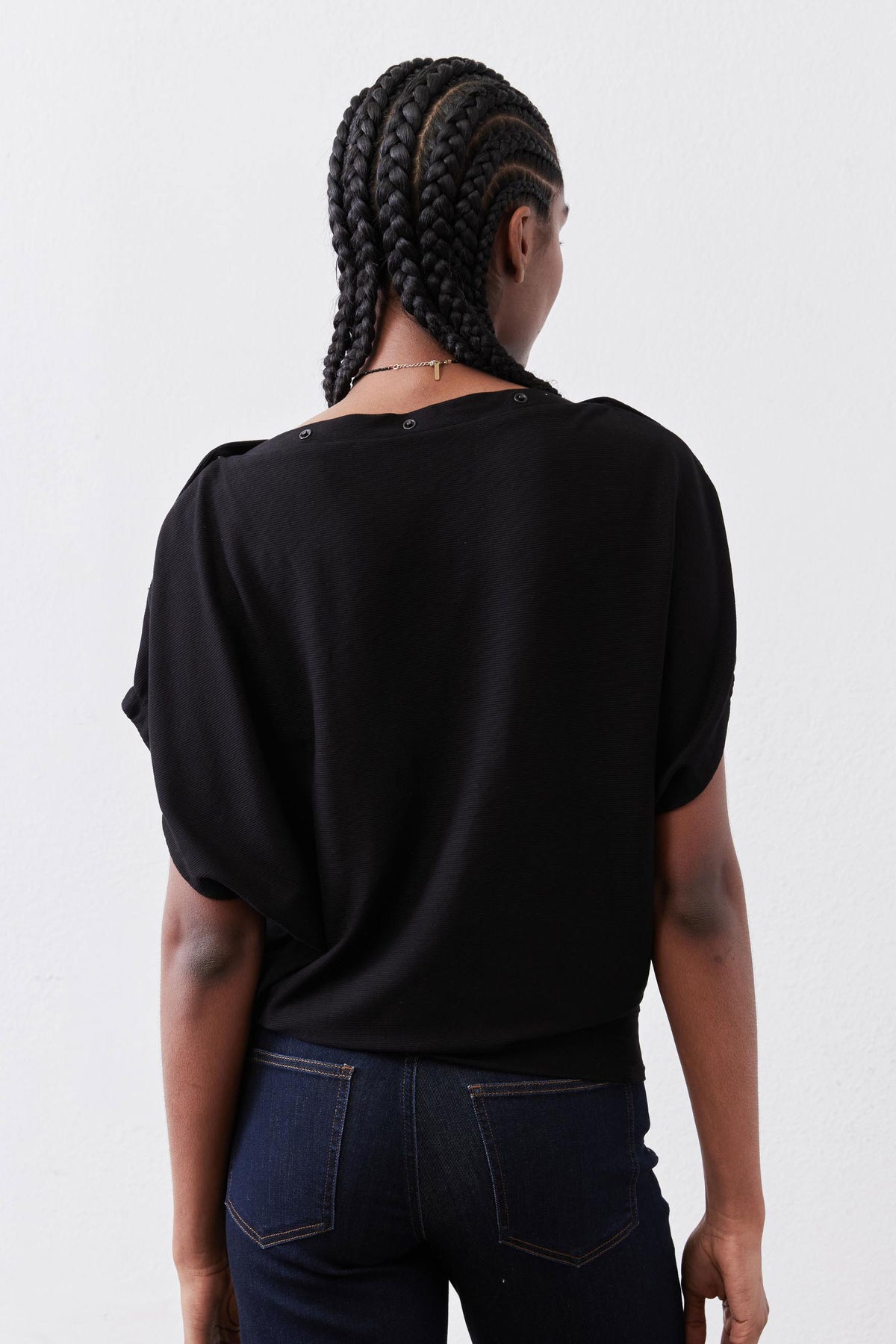 Black short-sleeve top with crew neck and relaxed back drape