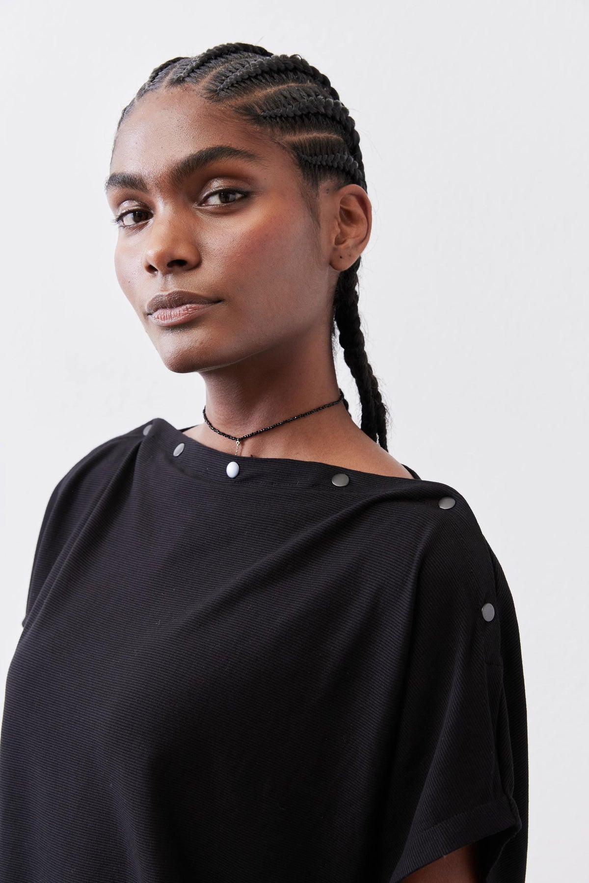 Black short-sleeve top with crew neck and snap-button shoulder detail