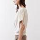 Cream short-sleeve draped top with round neckline and shoulder buttons