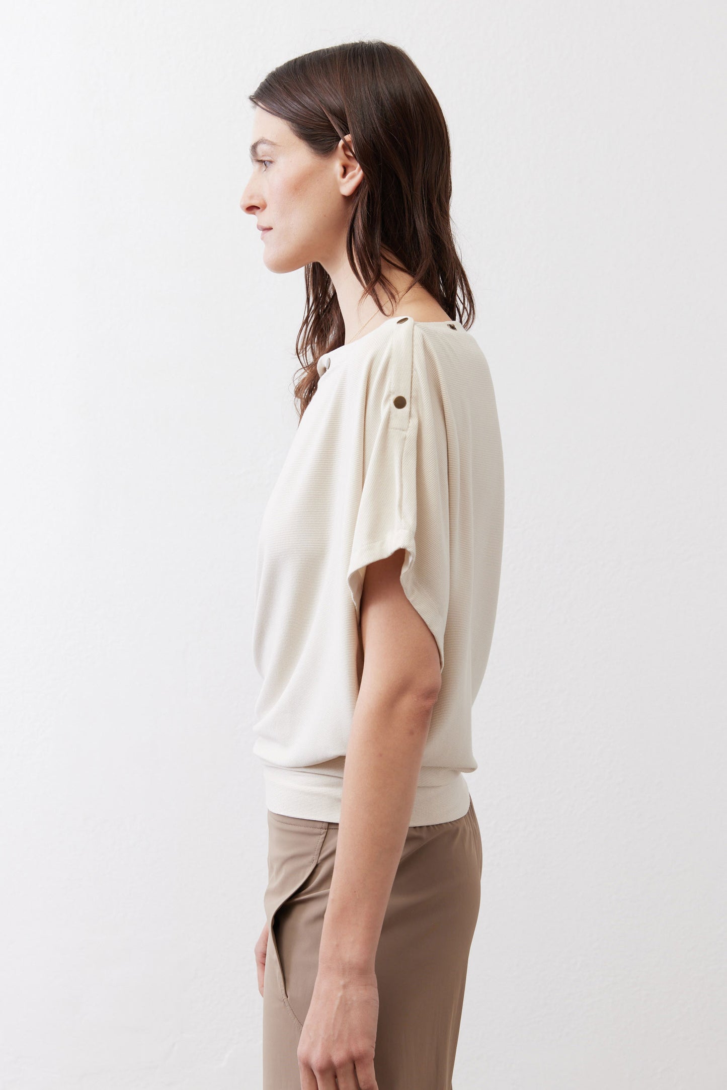 Cream short-sleeve draped top with round neckline and shoulder buttons