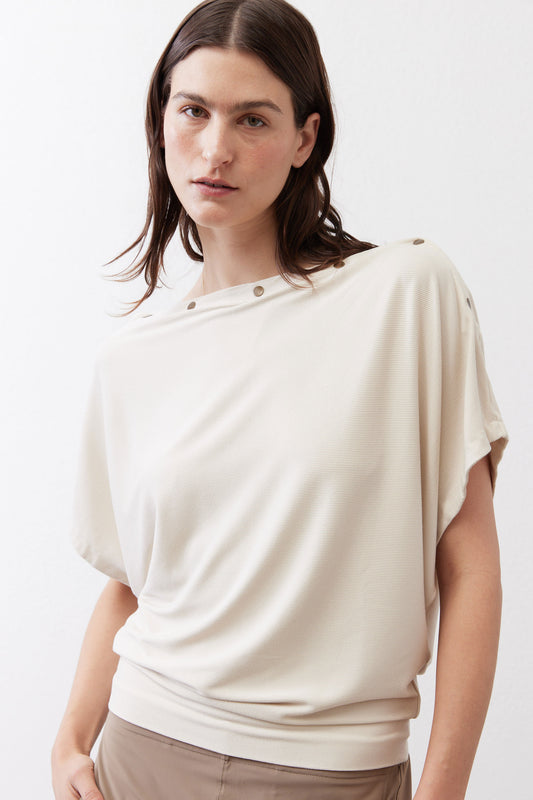Ivory short-sleeve top with snap-button neckline, relaxed drape and shoulder detail, close-up