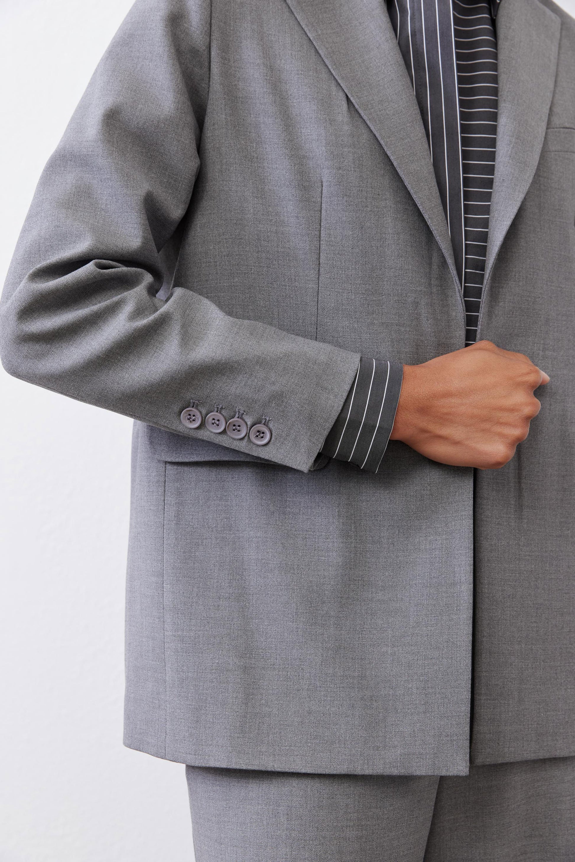 Gray melange blazer sleeve and cuff detail with four decorative buttons