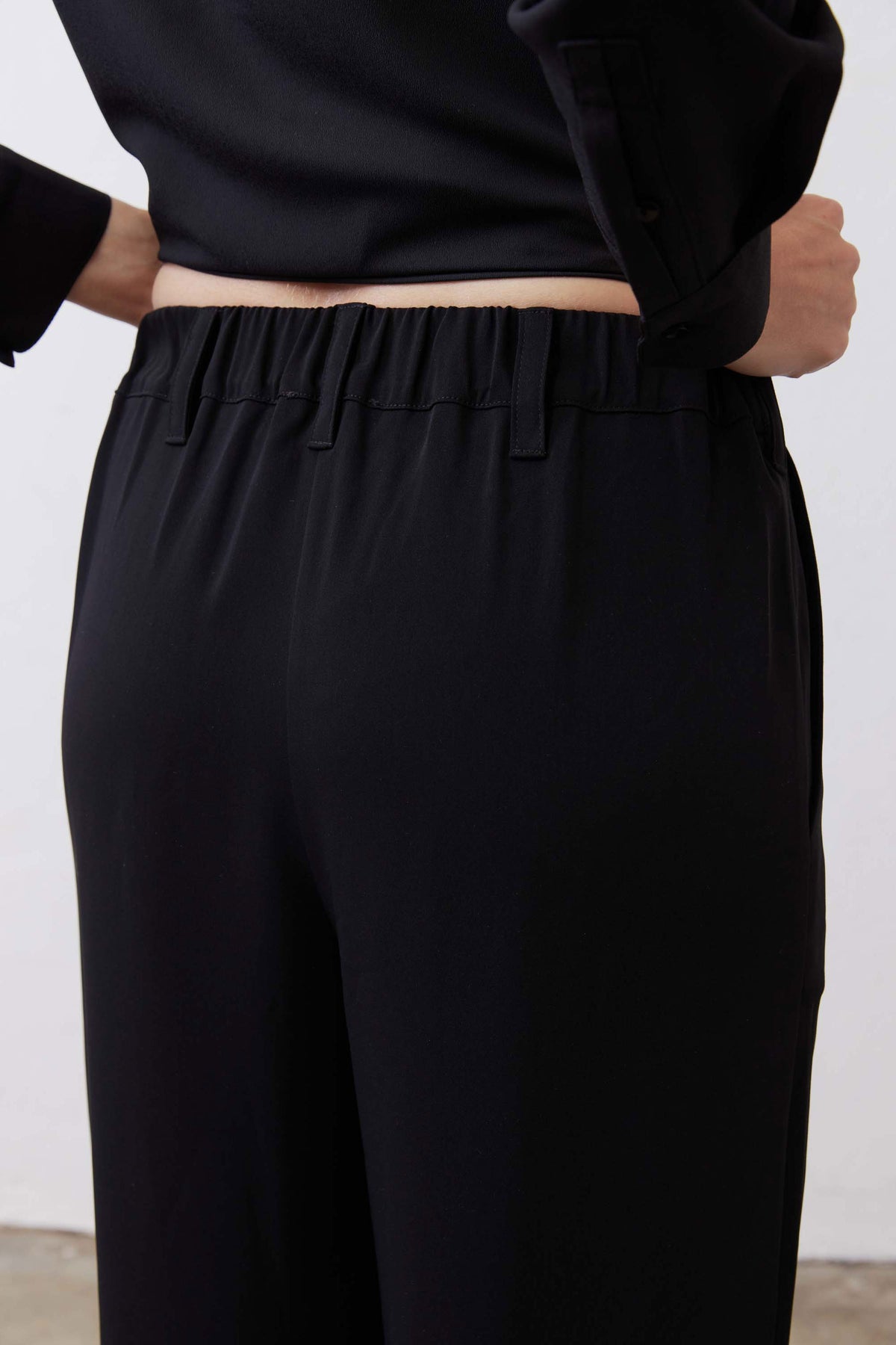 Black straight-leg pants waistband with belt loops and stitched pleats