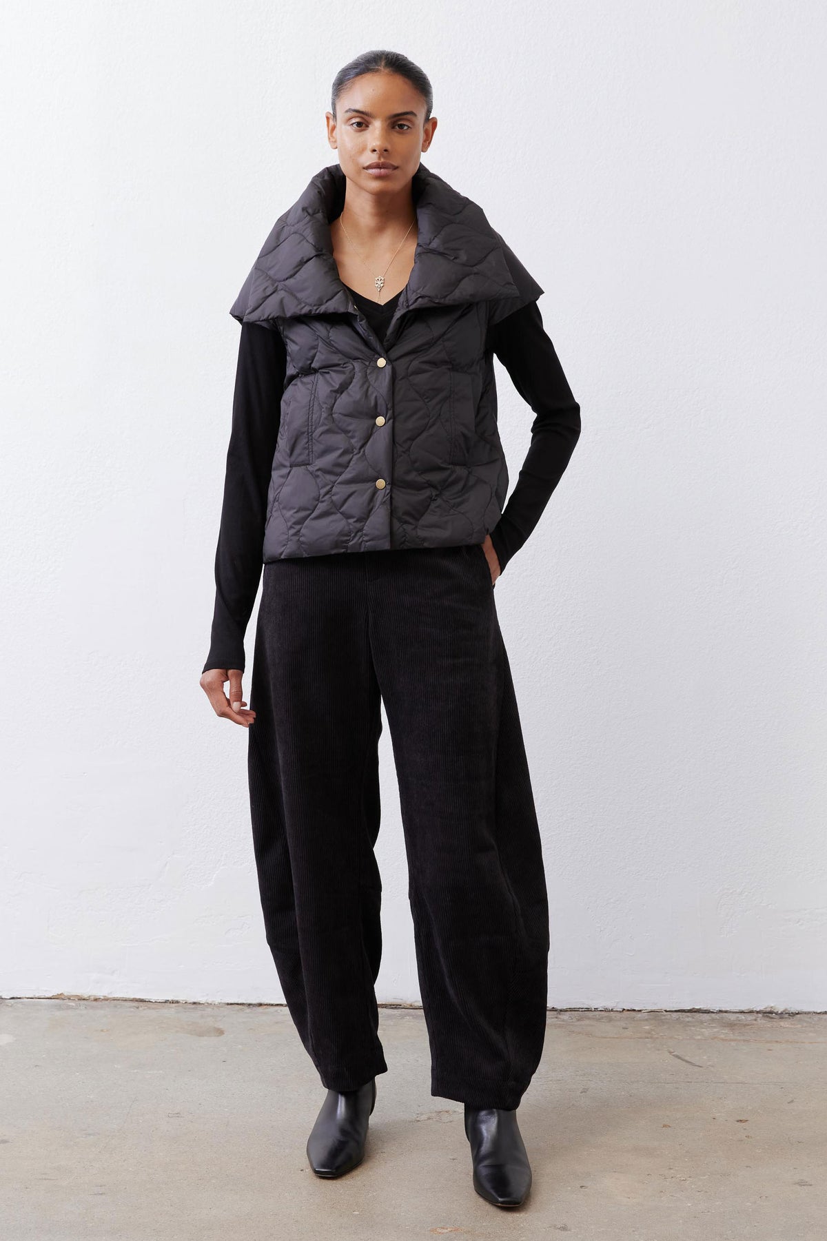 Black quilted down vest with oversized collar and gold snap front