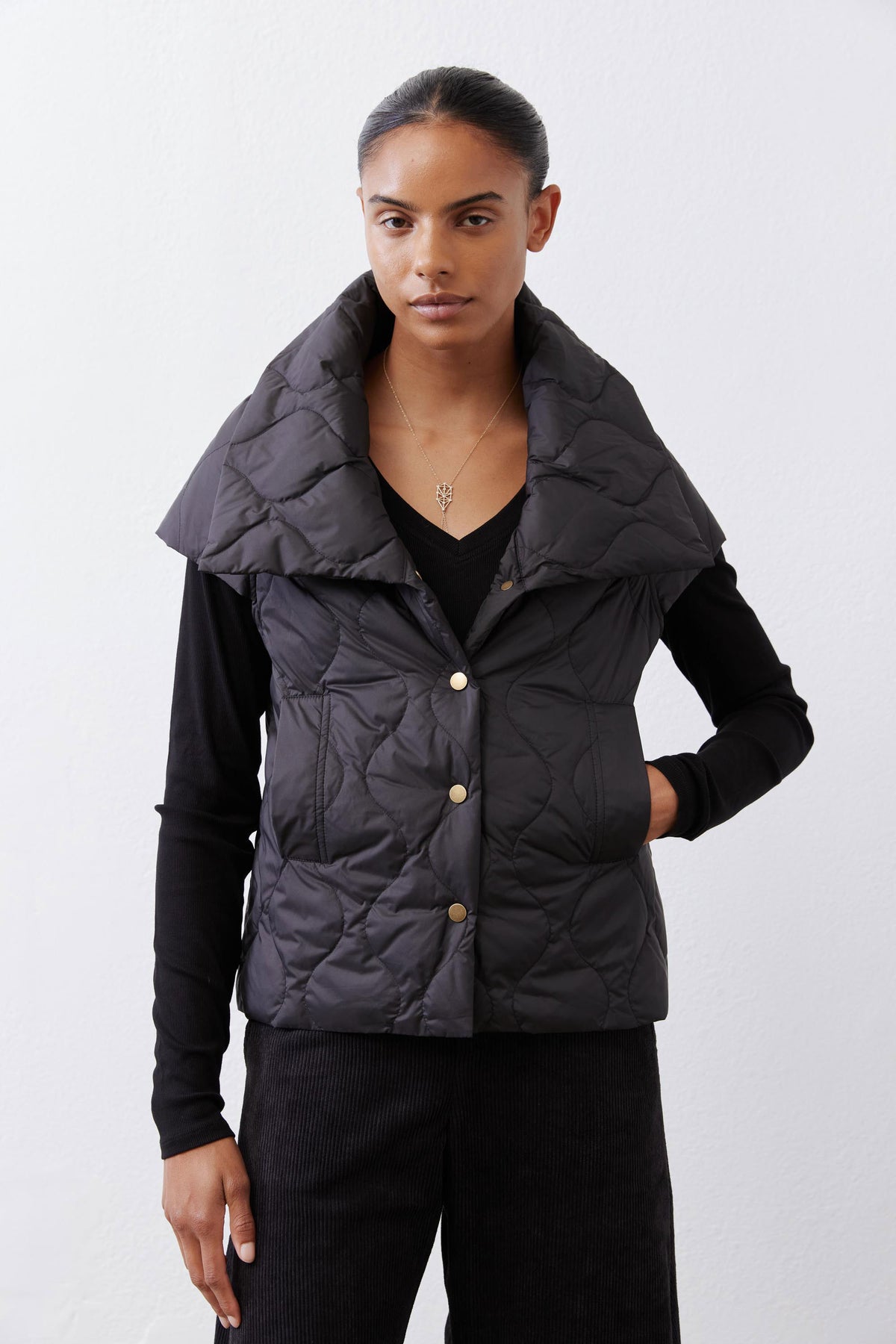 Black quilted down vest, front view, stand collar with gold snap buttons