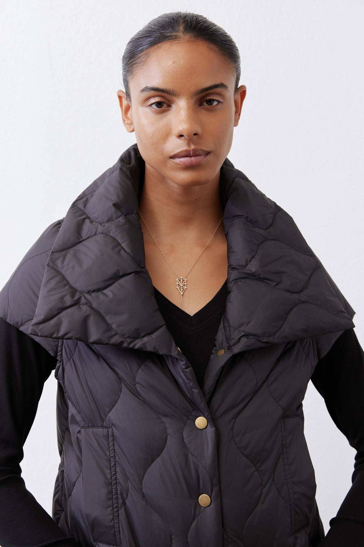 Black quilted down vest close-up with gold snap buttons and quilted texture