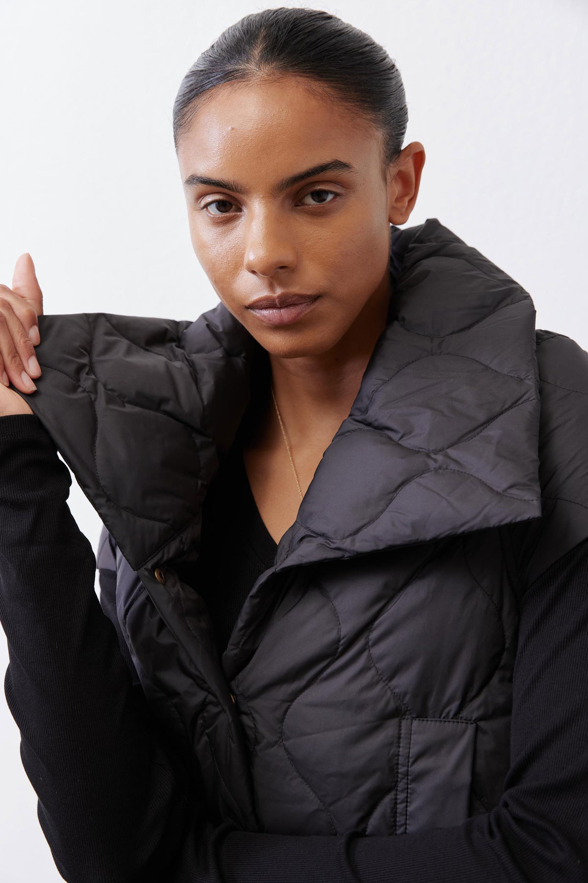 Black quilted down vest close-up with stand collar and gold snap placket