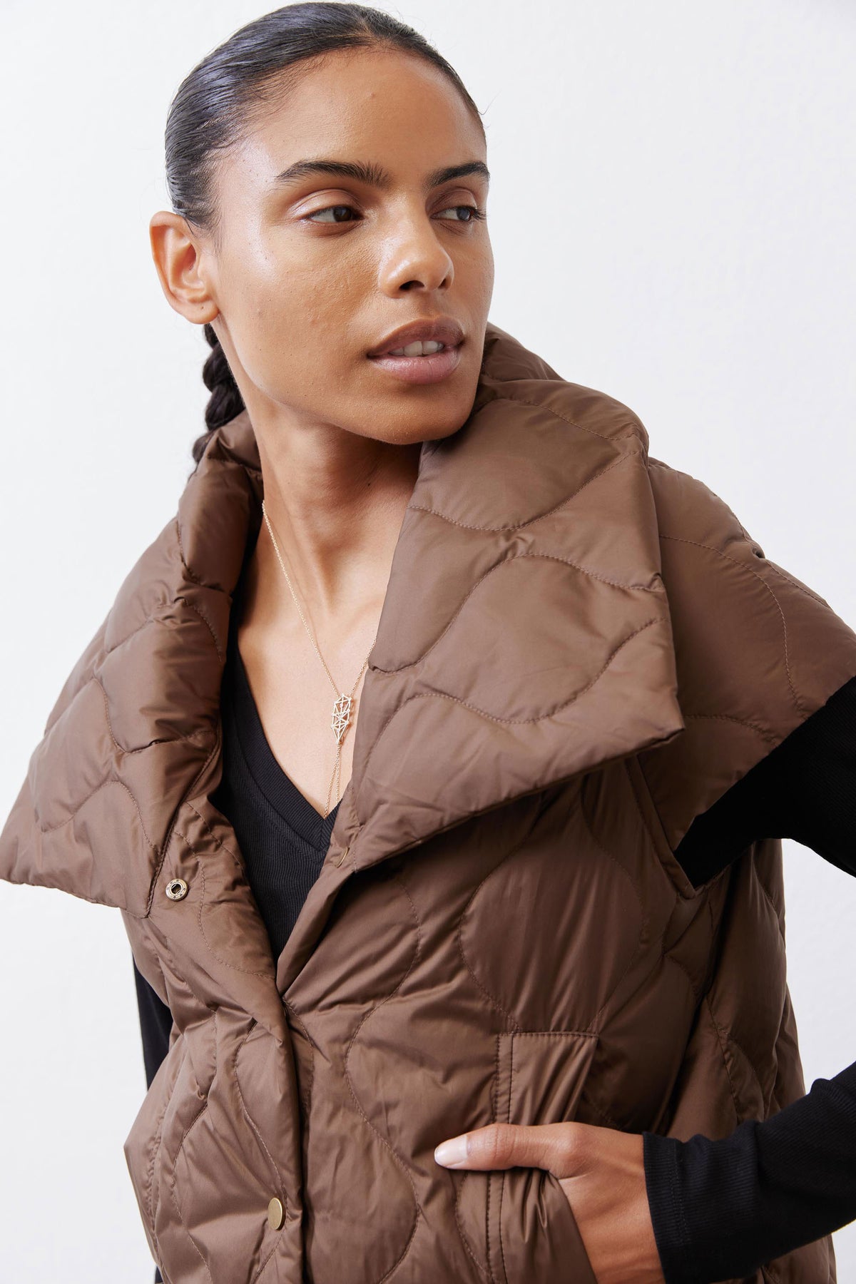 Quilted down vest in coffee brown with button placket and chest pocket, angled close-up