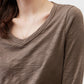 Brown V-neck top close-up with draped neckline and long sleeves