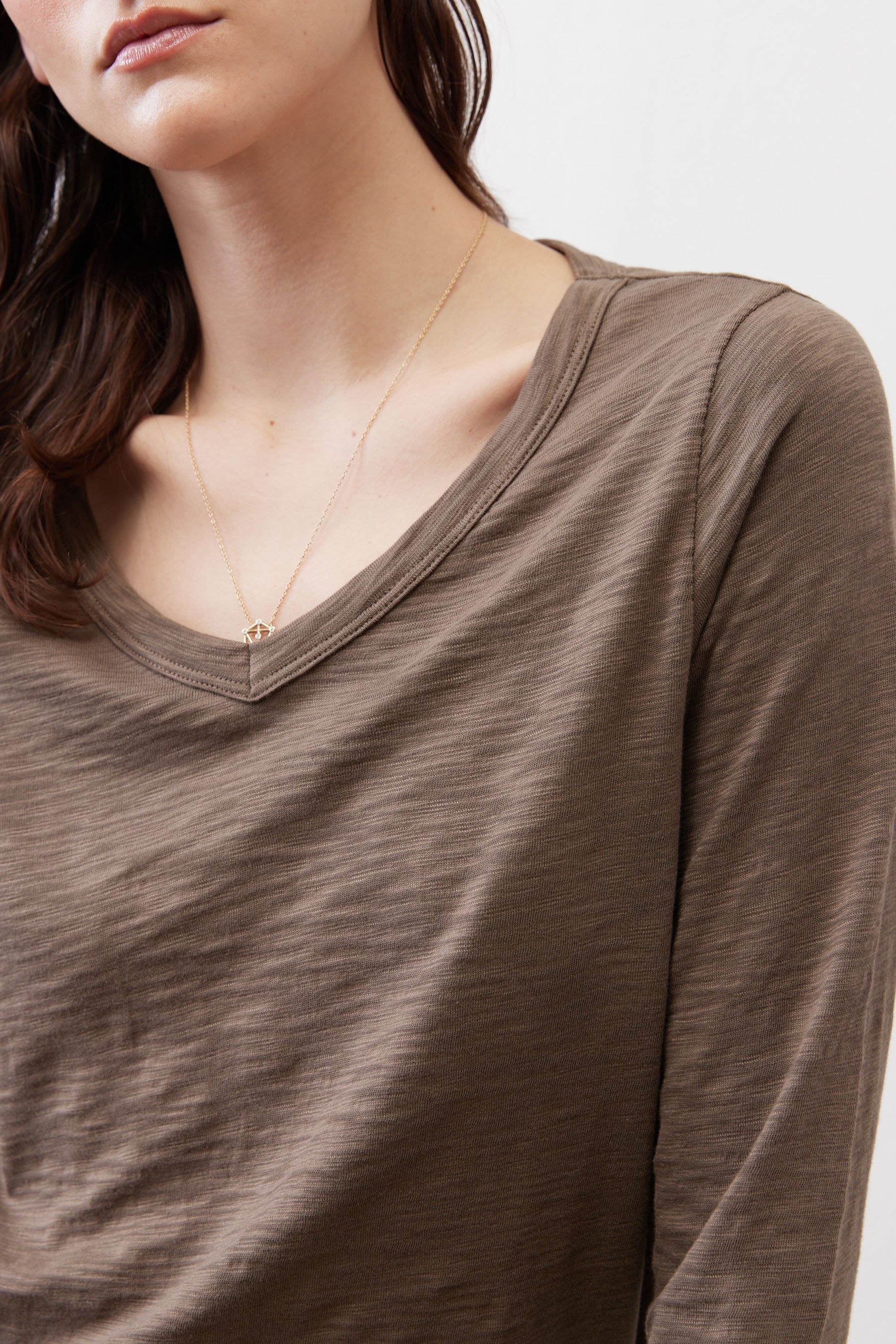 Brown V-neck top close-up with draped neckline and long sleeves