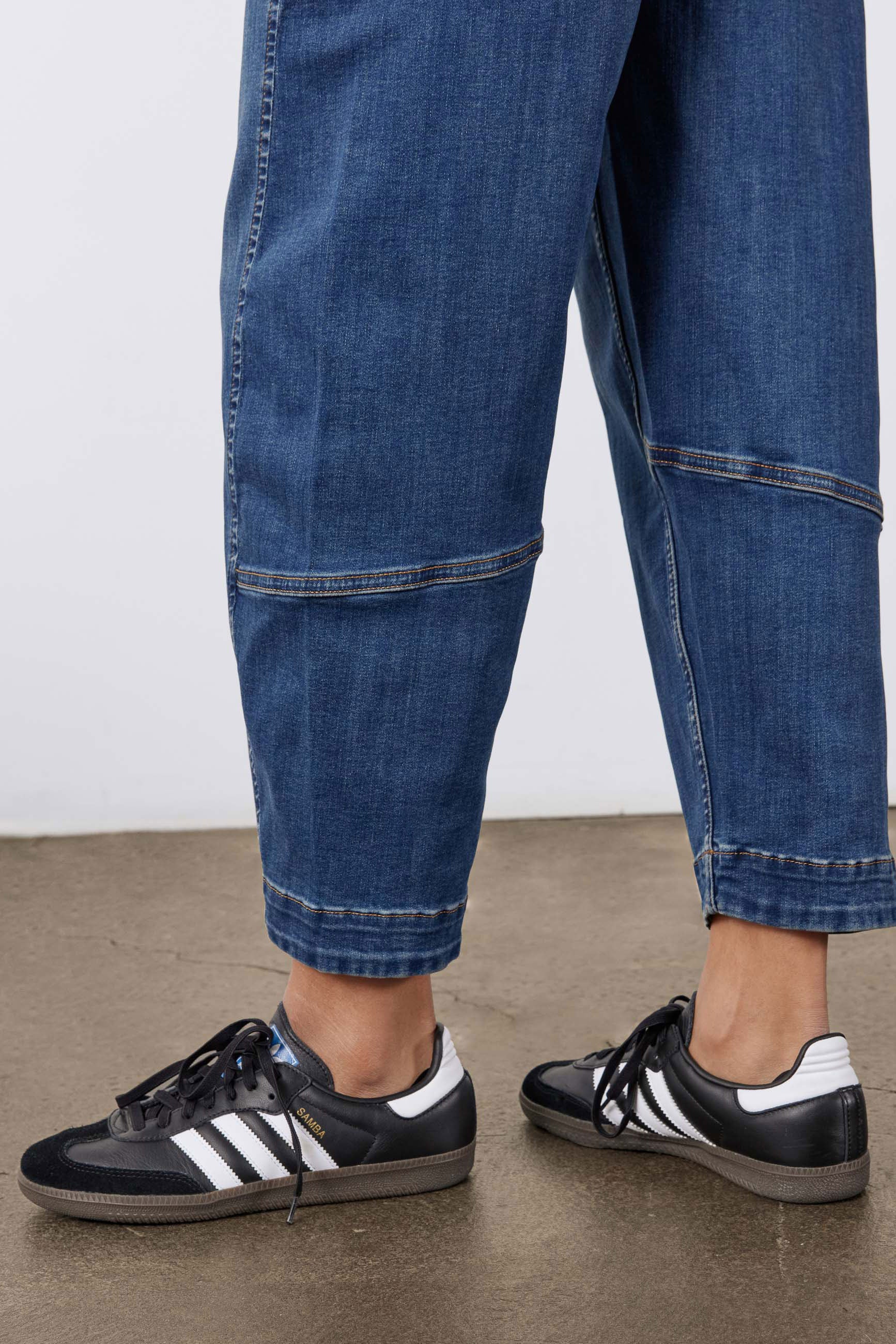 Indigo jeans leg close-up with contrast-stitched cuffs and rolled hem