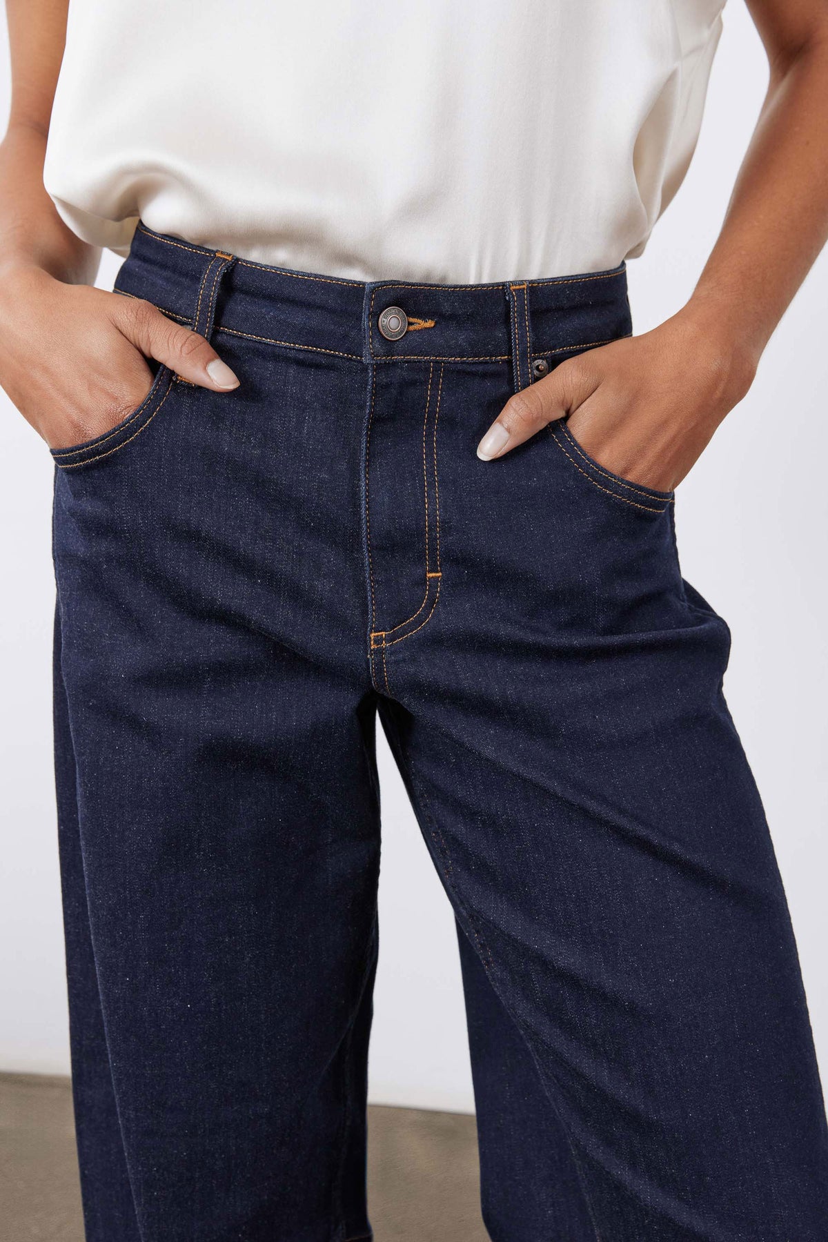 Dark wash barrel-leg jeans close-up of front pockets, coin pocket, and button
