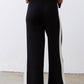 Black lounge pants with vertical ivory stripe and wide-leg hem