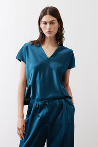 Deep teal V-neck short-sleeve top with draped front and waist tie, model front view