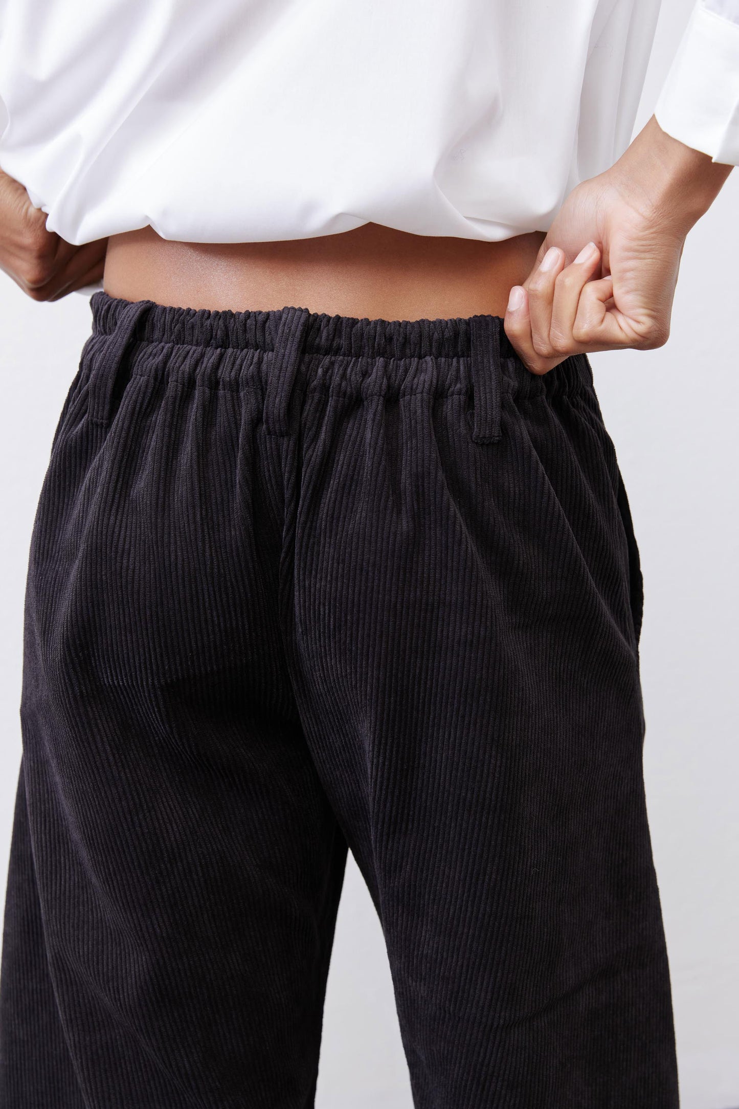 Black corduroy pants with elastic waistband and relaxed pleated front