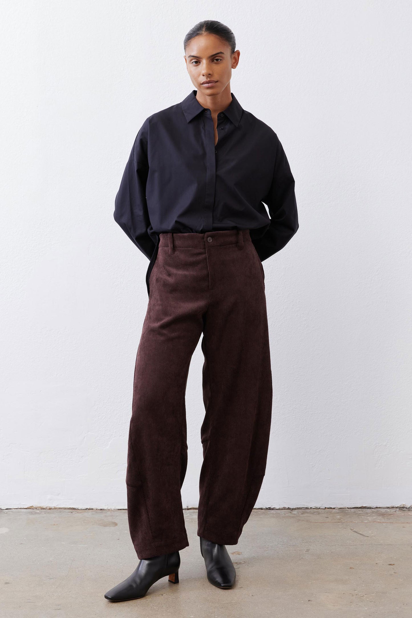 Chocolate-plum corduroy barrel pants on model, relaxed straight legs with pockets