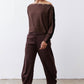 Chocolate-plum corduroy barrel pants on model, side view of relaxed leg shape