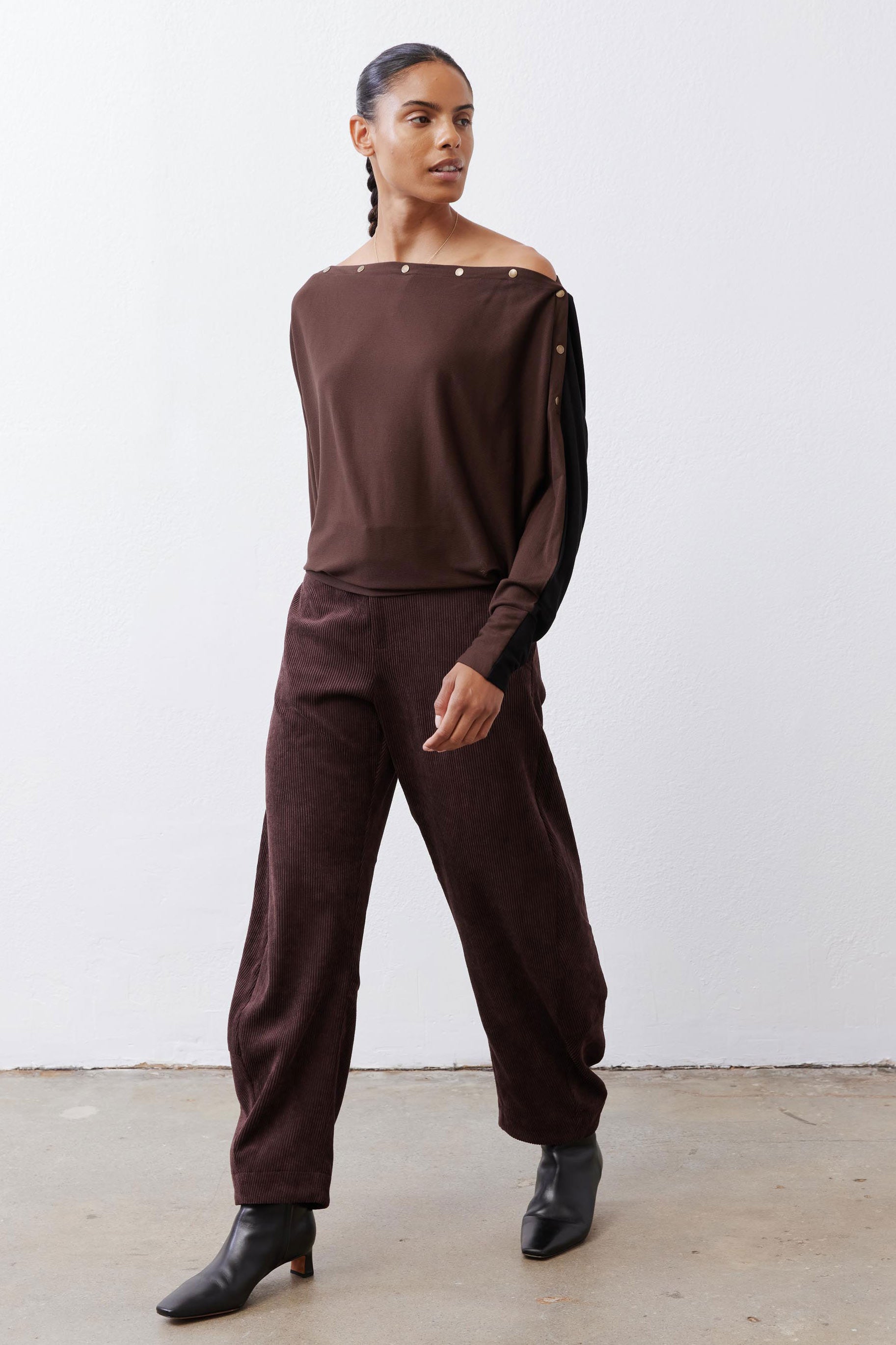 Chocolate-plum corduroy barrel pants on model, side view of relaxed leg shape