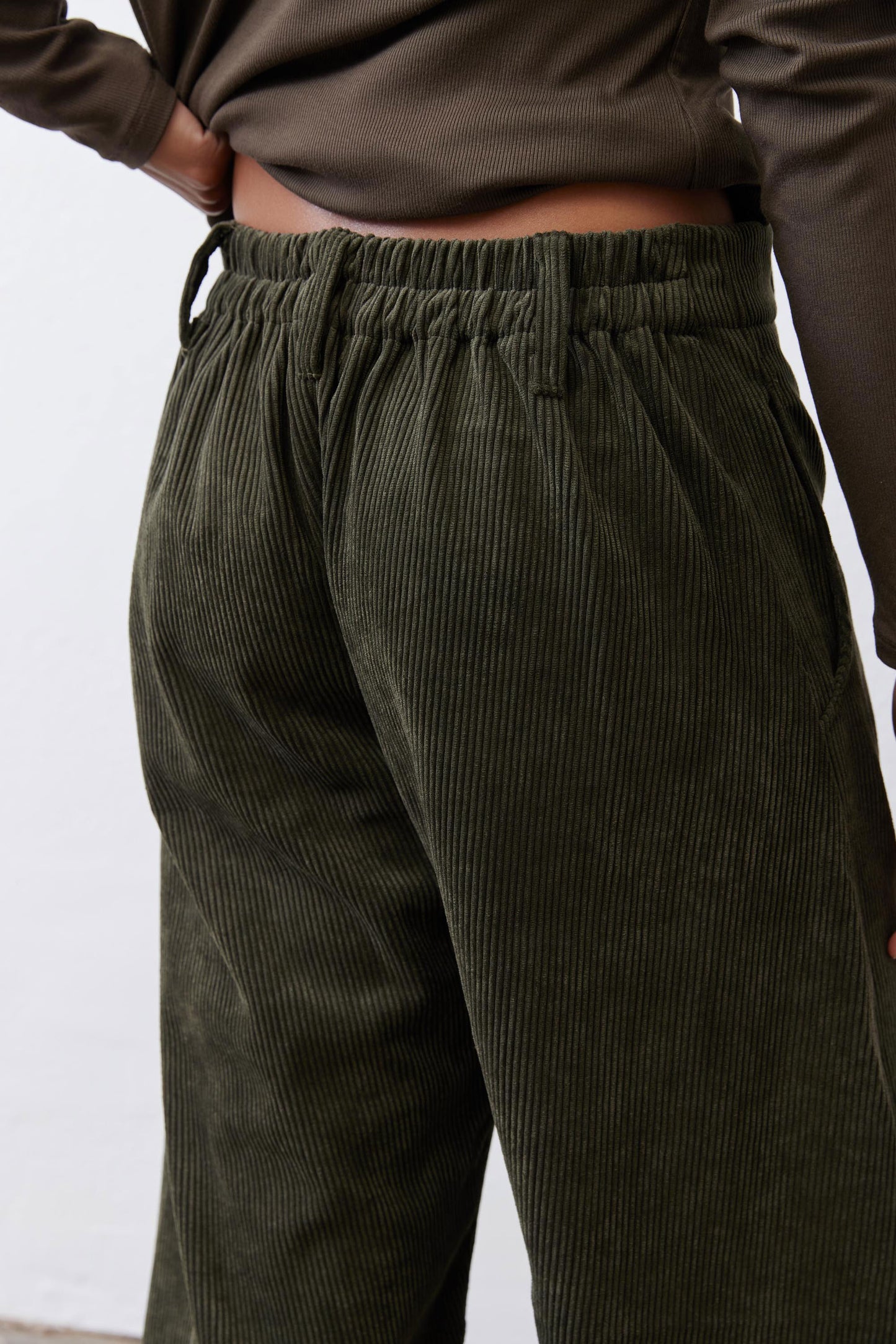 Dark green corduroy barrel pants close-up: gathered elastic waistband detail