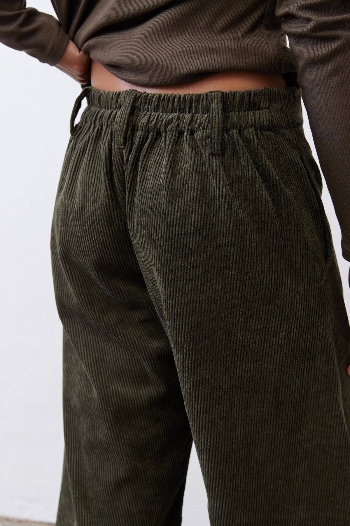 Dark green corduroy barrel pants close-up: gathered elastic waistband detail