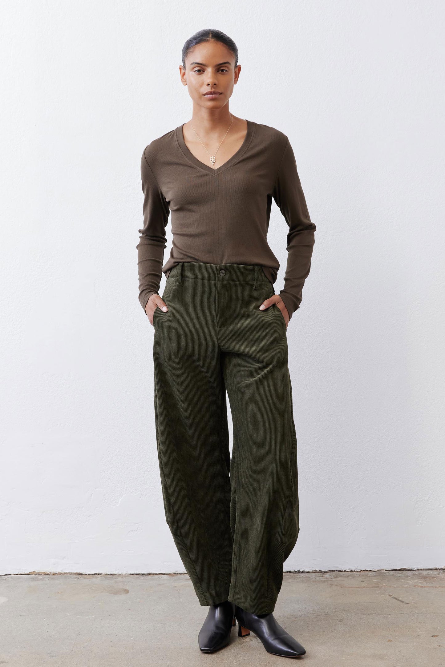 Dark green loose corduroy barrel pants with elastic waist and wide, draped legs