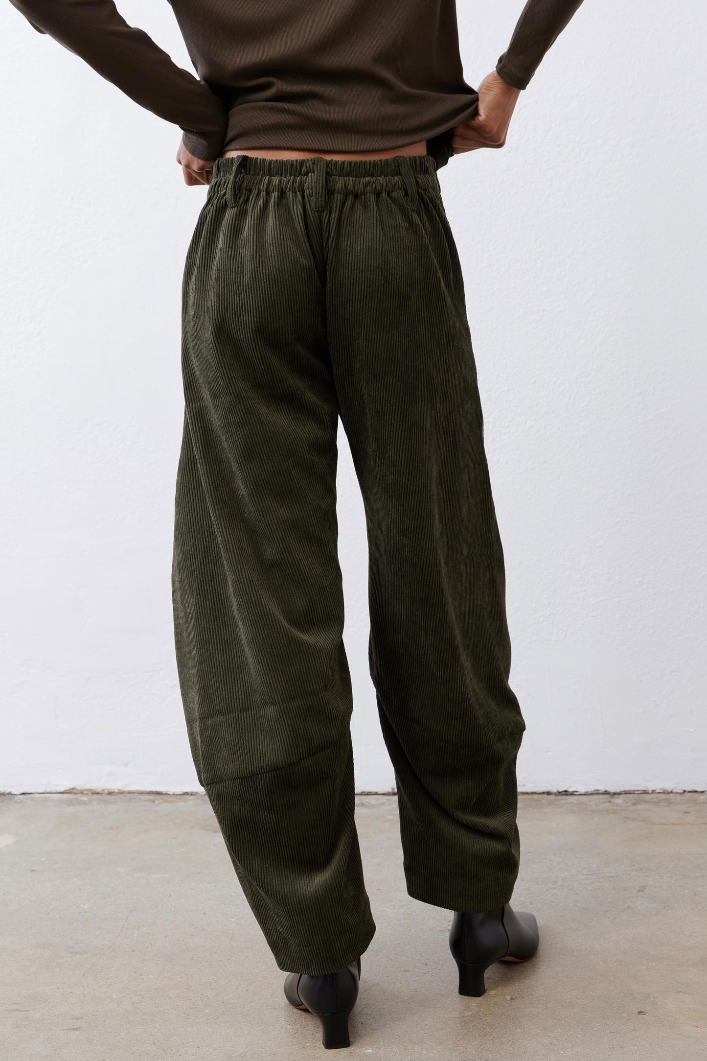 Dark green corduroy barrel pants with elastic waistband and cuffed, roomy ankles