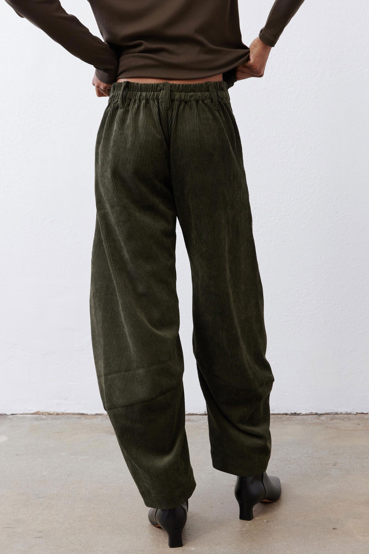 Dark green corduroy barrel pants with elastic waistband and cuffed, roomy ankles