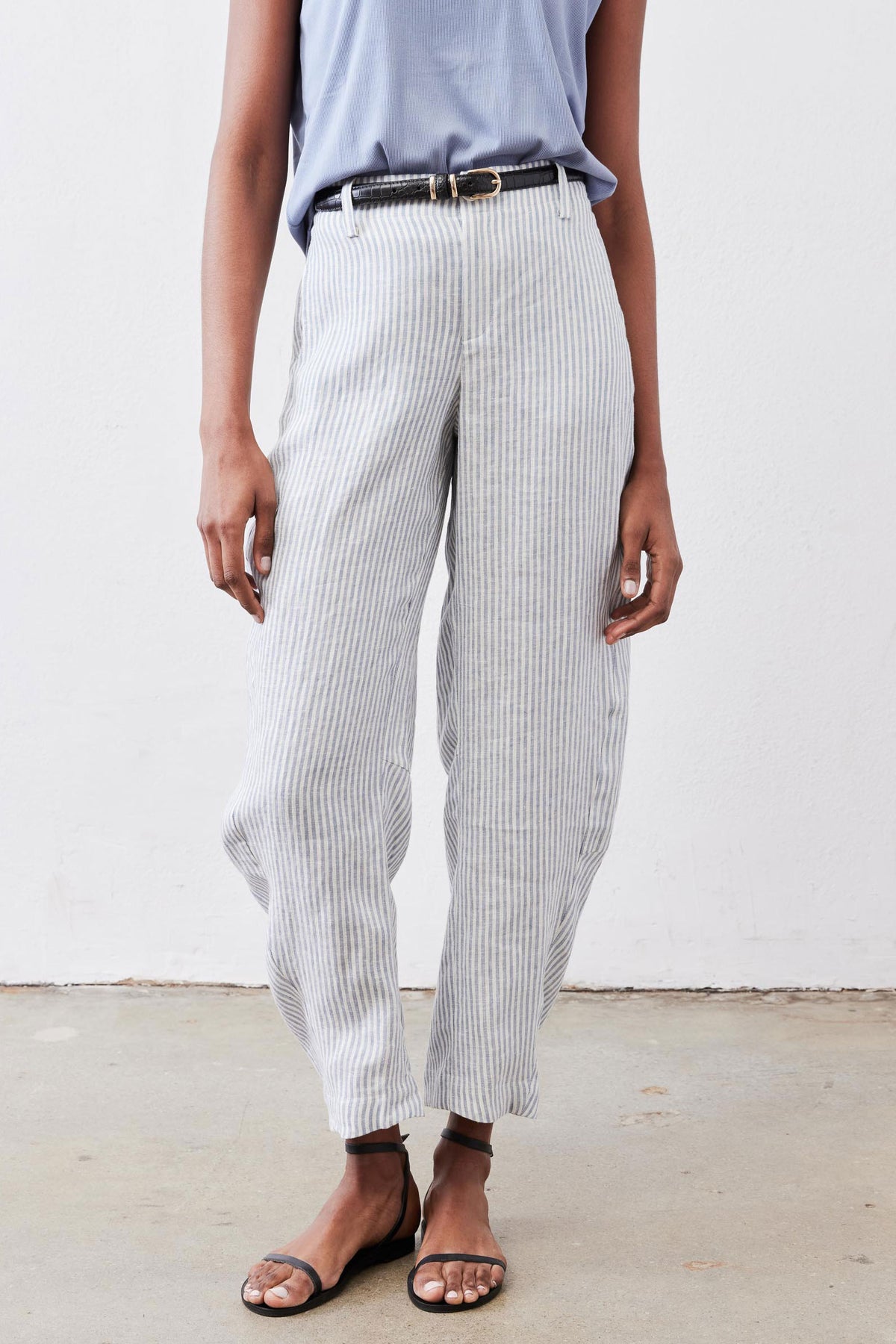 Loose linen pants with thin vertical stripes, relaxed straight legs and waist belt