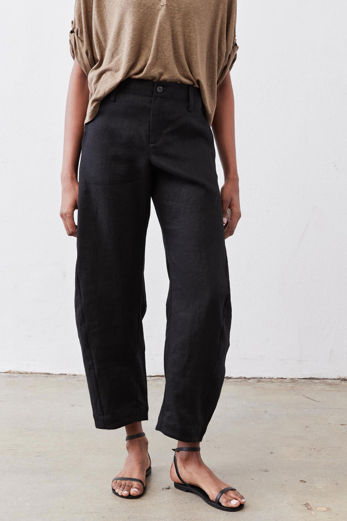 Black loose linen pants with button front and roomy tapered legs, ankle-length hem