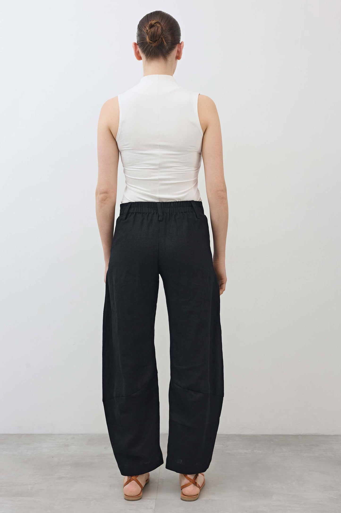 Black linen pants from back view with elastic waistband and relaxed tapered leg shape
