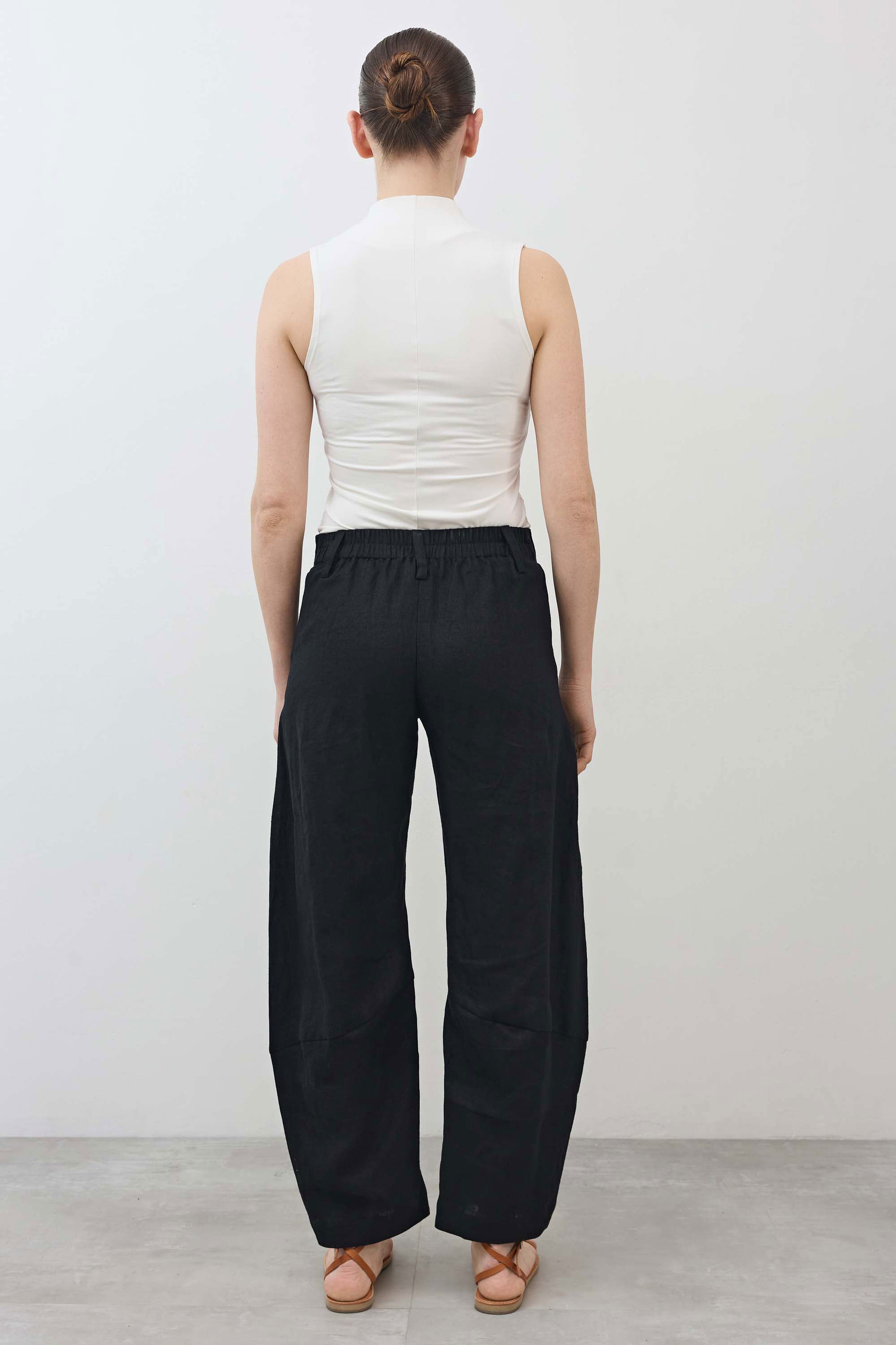 Black linen pants from back view with elastic waistband and relaxed tapered leg shape
