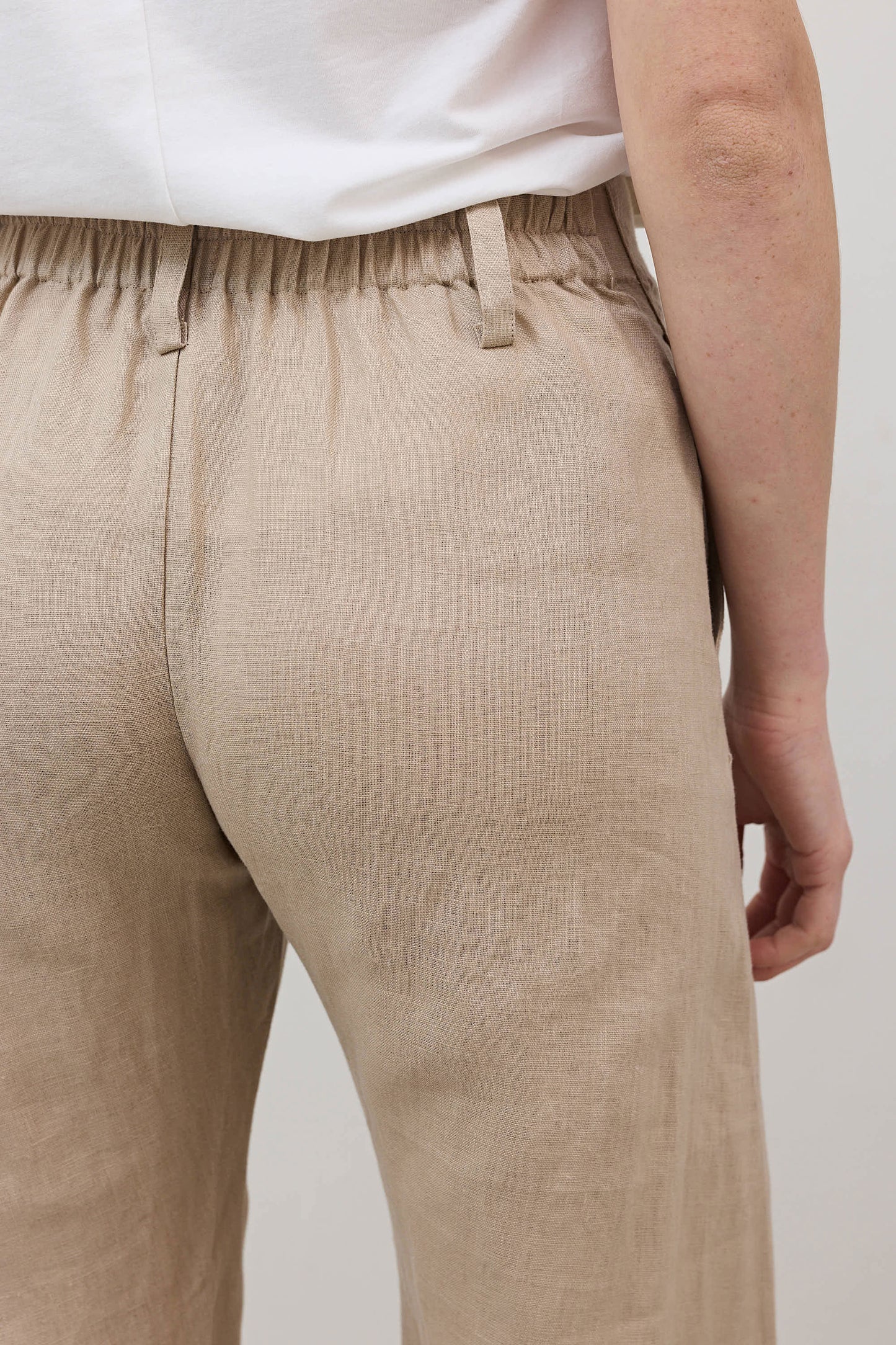 Light beige linen pants close-up, elastic waistband with stitched seam and pocket opening