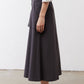 Graphite utility skirt side profile, midi hem with panel seams and cargo pocket.