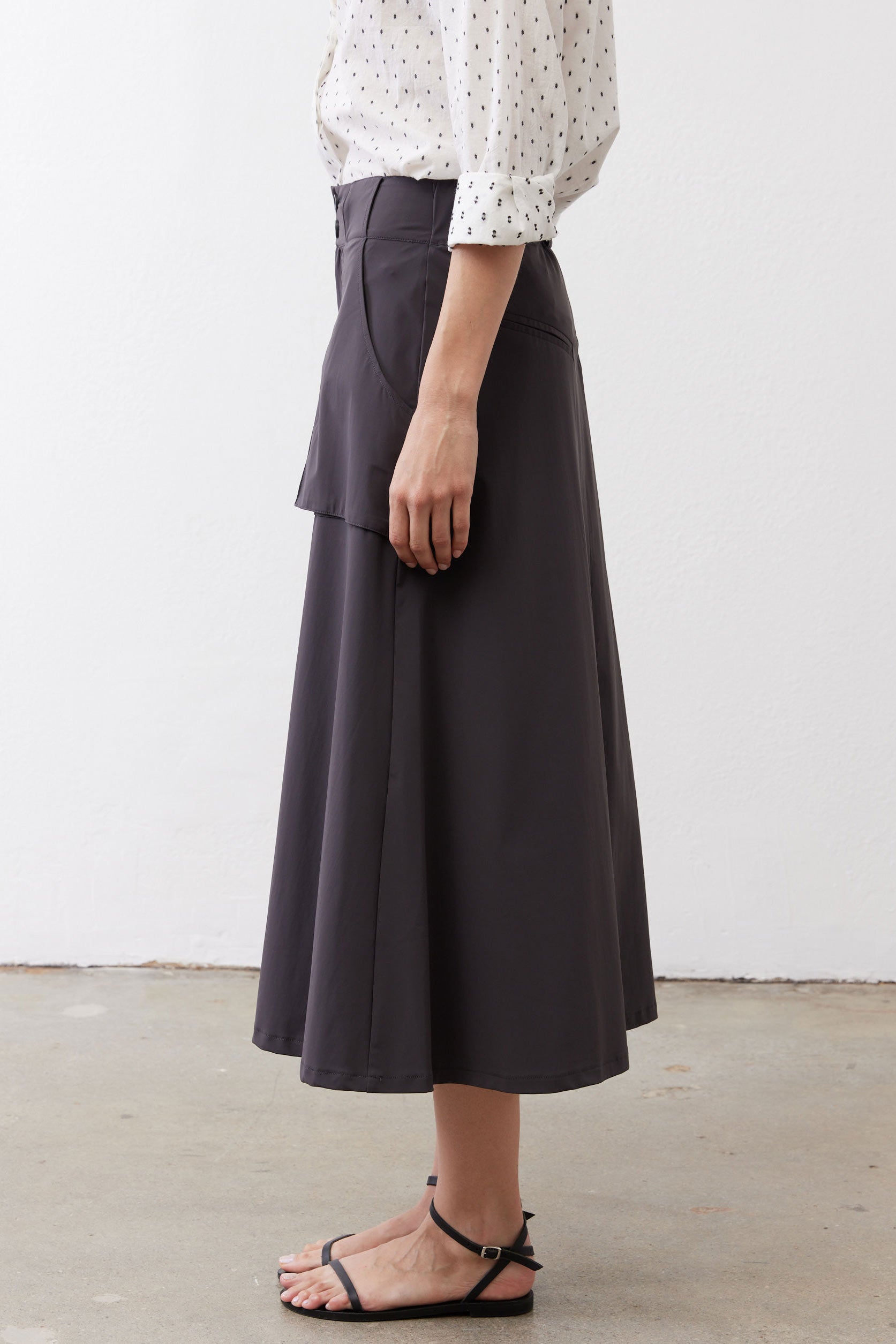 Graphite utility skirt side profile, midi hem with panel seams and cargo pocket.