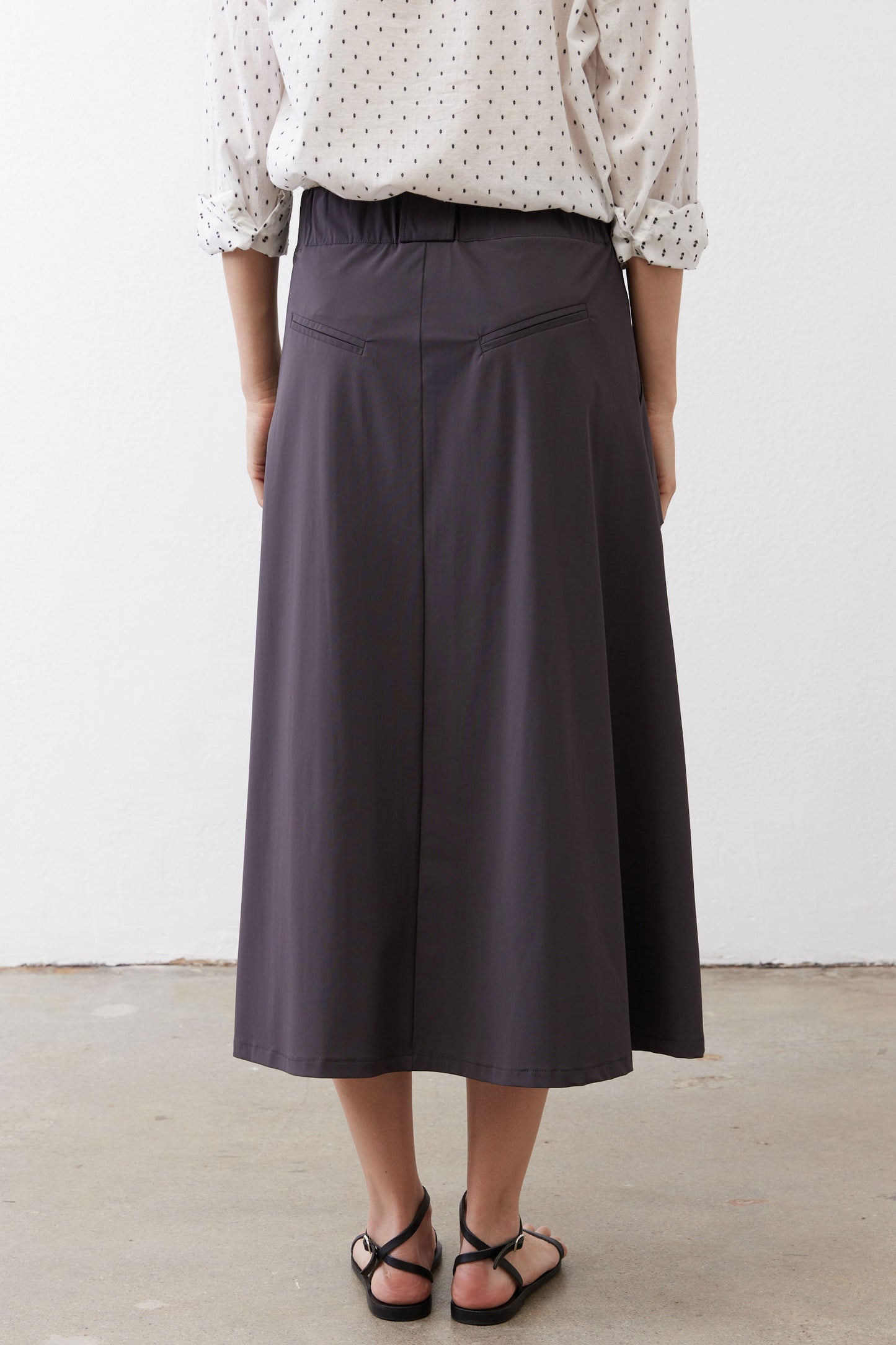 Graphite utility skirt back view, midi length with pleated center and belt loops.