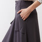 Graphite utility skirt pocket flap detail with stitched front seams and paneling.