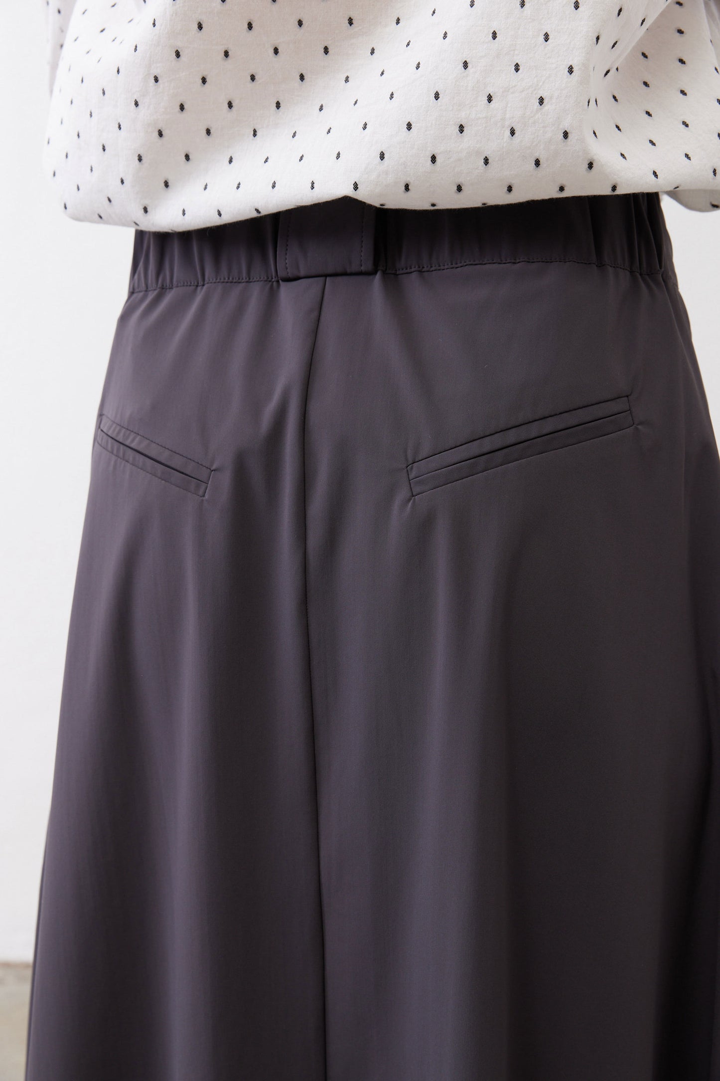 Graphite utility skirt waistband and side pockets, structured panel seam detail.
