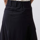 Black utility skirt front close-up with button waistband and pleated skirt panels