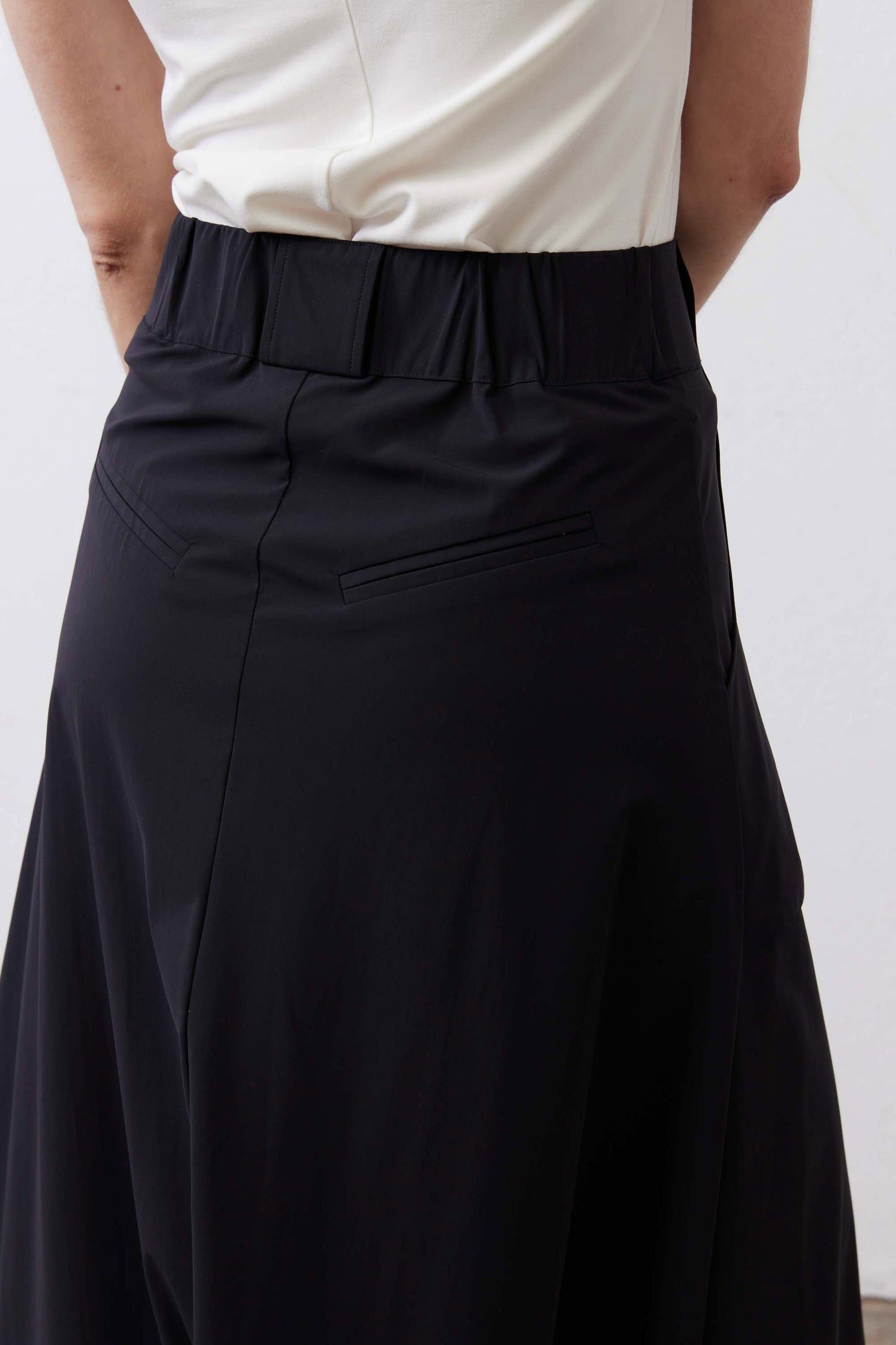Black utility skirt front close-up with button waistband and pleated skirt panels