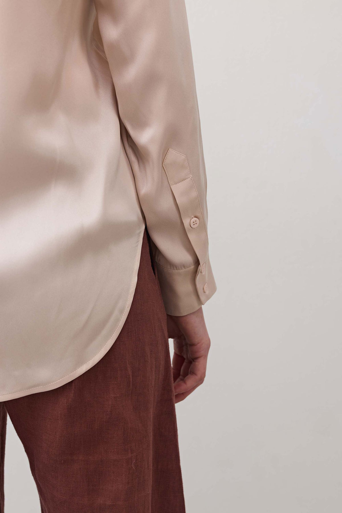 Peach blush silk button-down top close-up of sleeve cuff and button detail