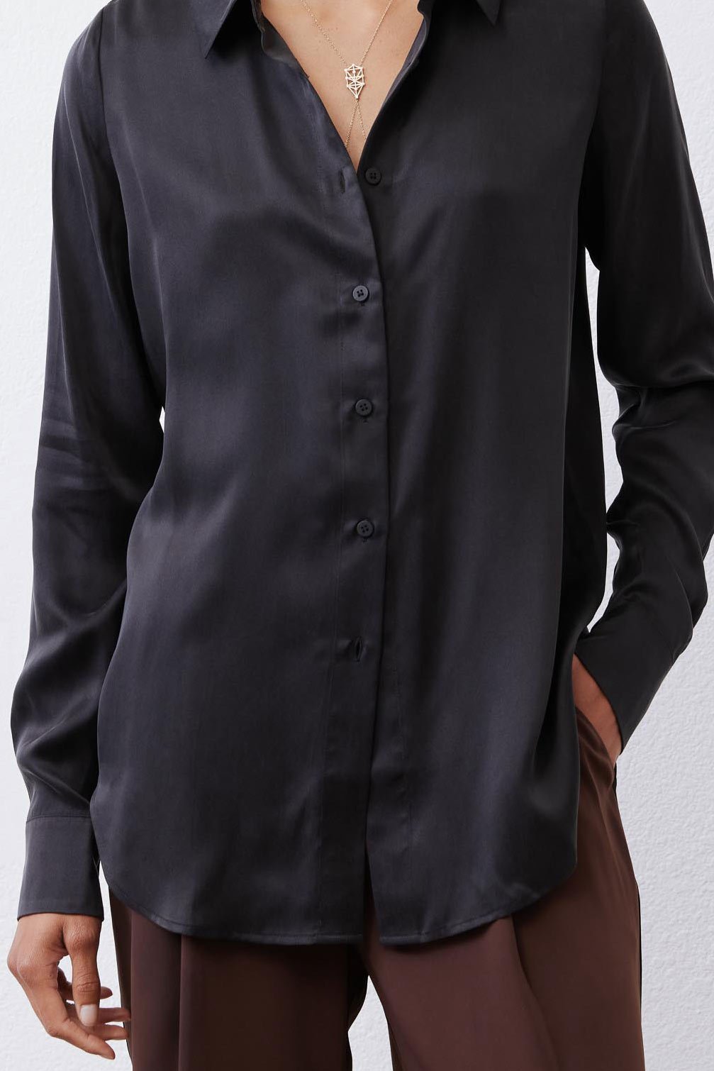Black silk button-down top close-up: button placket, pointed collar, long sleeve