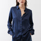 Dark blue silk button-down top on model, long sleeves and open collar