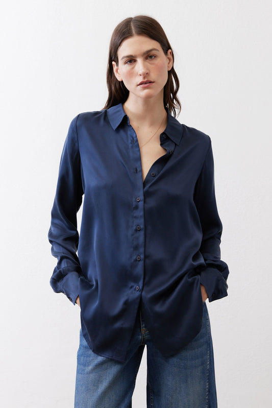 Dark blue silk button-down top on model, long sleeves and open collar