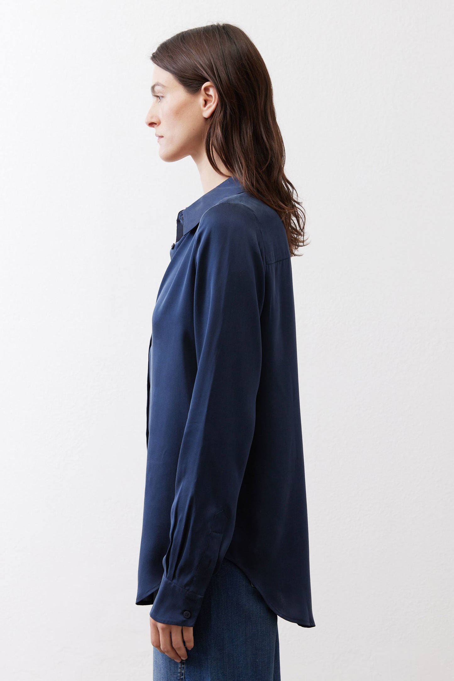 Dark blue silk button-down top side view with long sleeves and curved hem